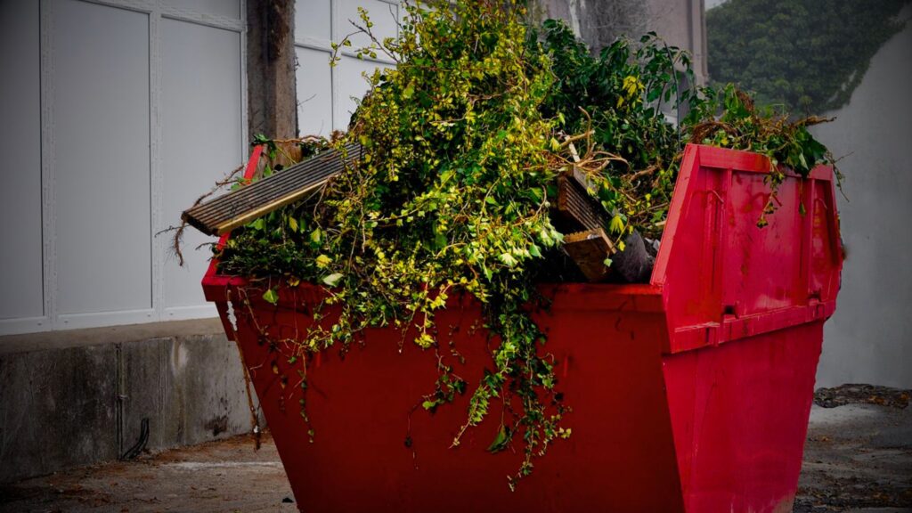 A red dumpster filled with plants, representing a unique combination of waste disposal and skip service