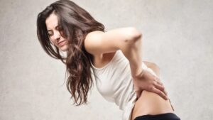 A woman holding her back, suffering from back pain